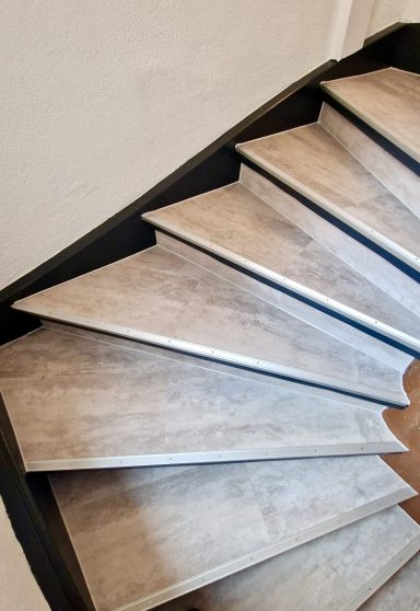 Holztreppe mit hellen, breiten Stufen in einem modernen Raum.