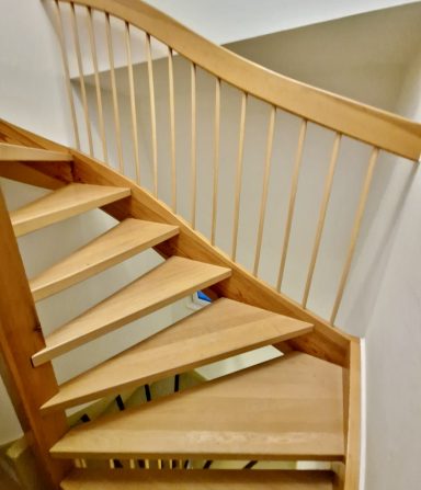 Schraubentreppe aus Holz mit handgefertigten Stufen und elegantem Geländer.
